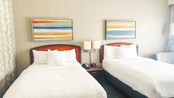 A hotel room with two beds, a carpeted floor, and two abstract paintings on the wall.