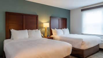 Une chambre d’hôtel avec deux lits, une table de chevet avec une lampe et une grande fenêtre.