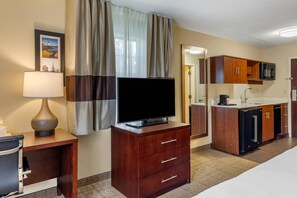 A hotel room with a flat-screen TV, wooden dresser, and a kitchenette with a microwave. - Comfort Inn Danvers - Boston North Shore (Danvers)