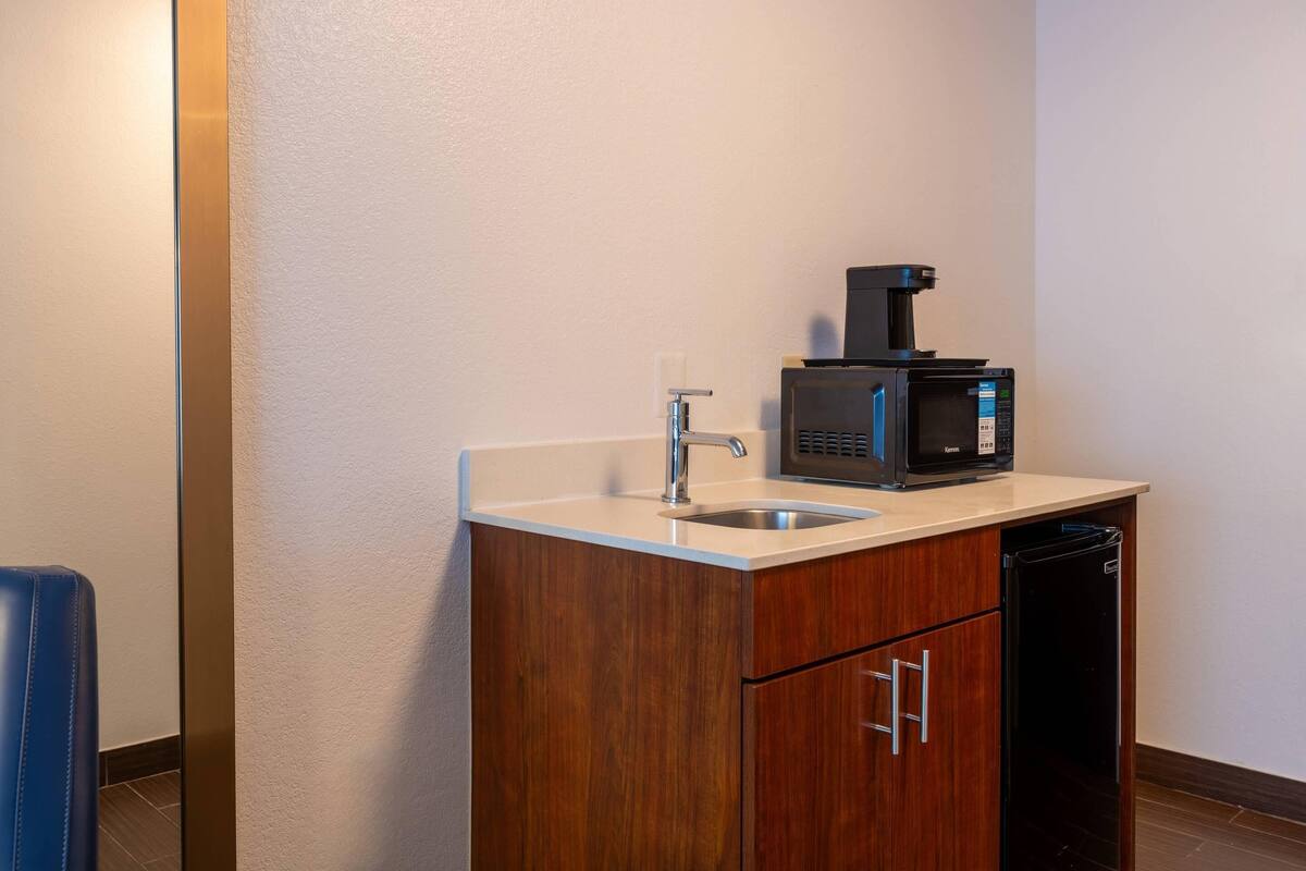 A small kitchenette with a sink, a coffee maker, and a microwave.