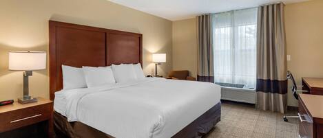 Una habitación de hotel con una cama grande, dos mesitas de noche con lámparas, un escritorio y una silla.
