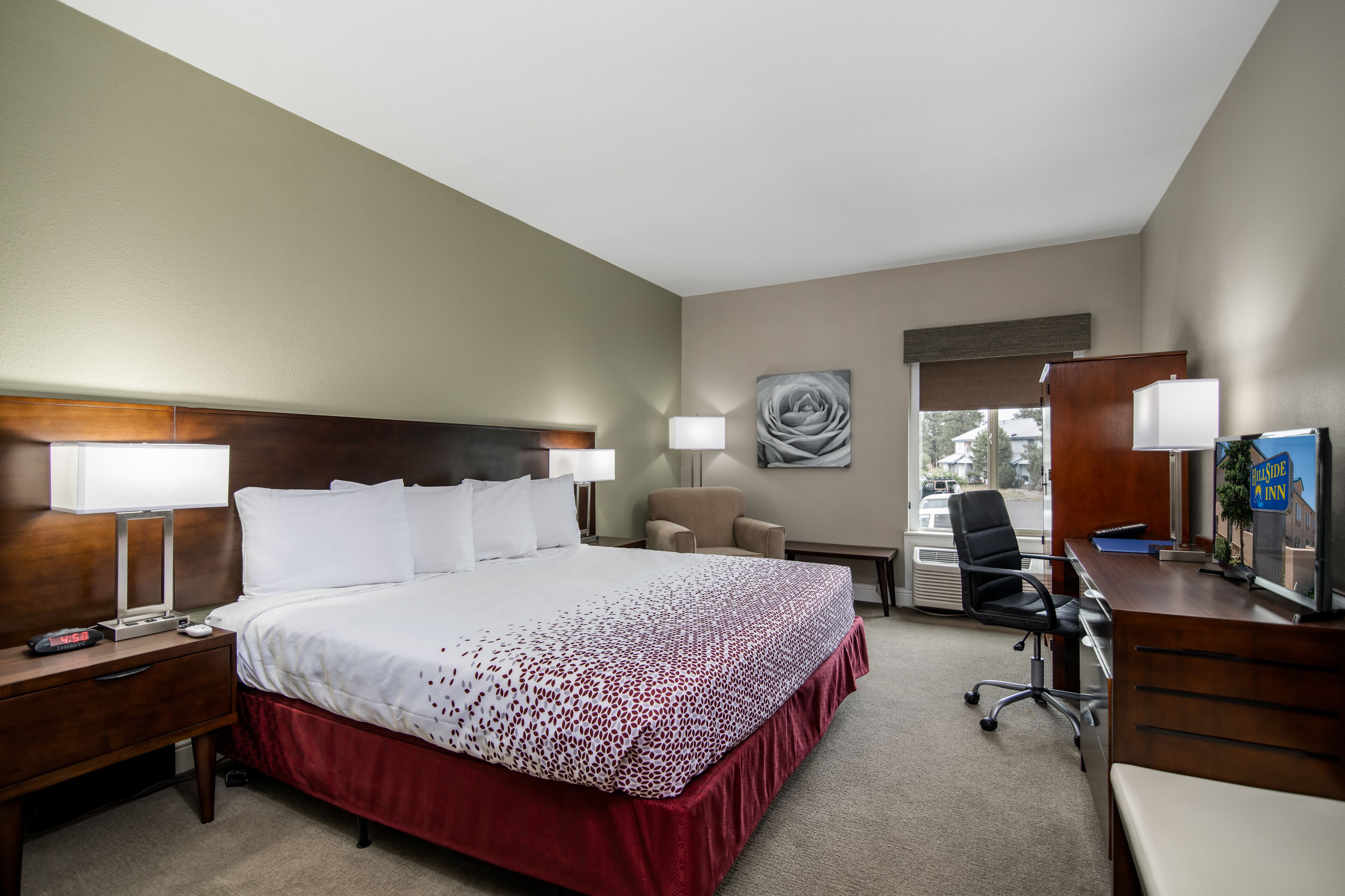 A hotel room with a large bed, two bedside tables, a desk, a chair, and a lamp.