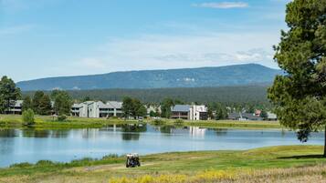 A lakeside view with buildings, a golf cart, and a mountain in the background.