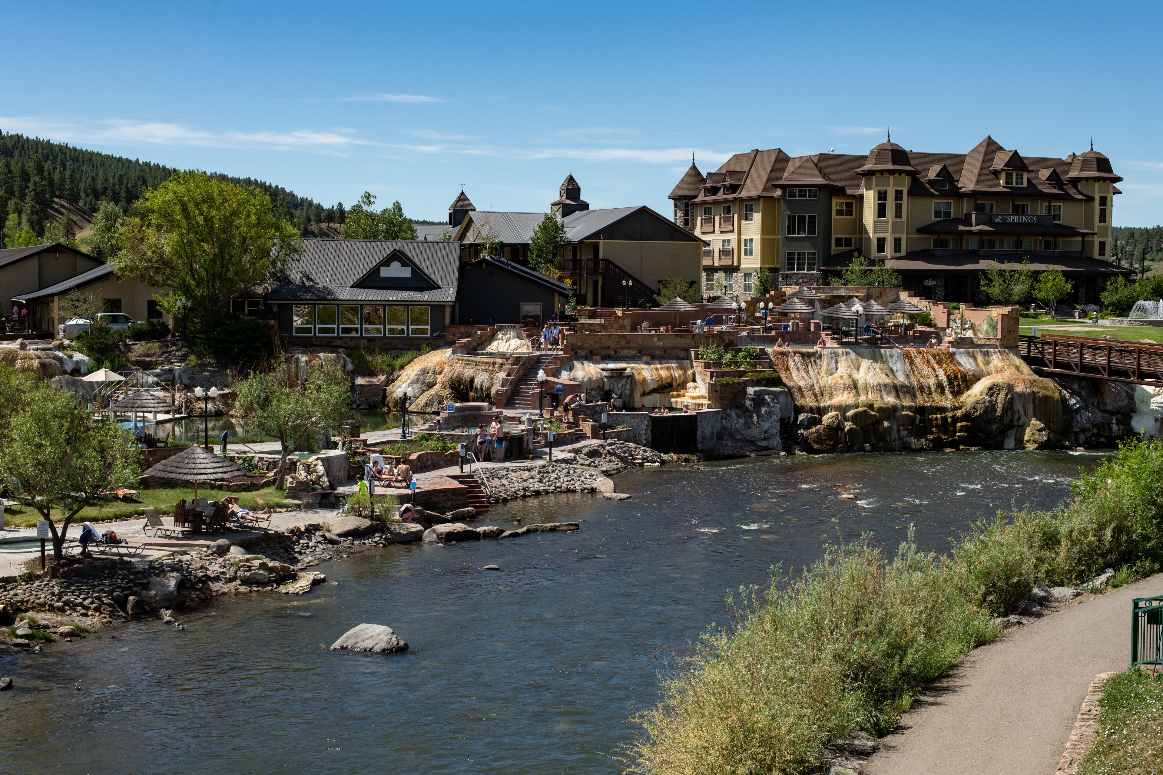 A riverside hotel with outdoor seating, a pool, and a view of the river.