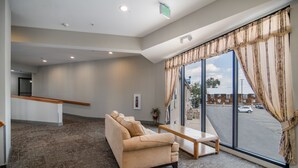 A spacious lobby with a beige sofa, a wooden bench, and large windows with curtains.