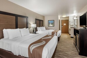 Ein Hotelzimmer mit zwei Betten, einem Schreibtisch, einem Fernseher und einem Badezimmer.