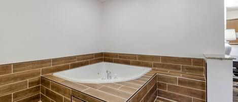 A modern bathroom with a freestanding bathtub, wooden floor tiles, and a white wall.
