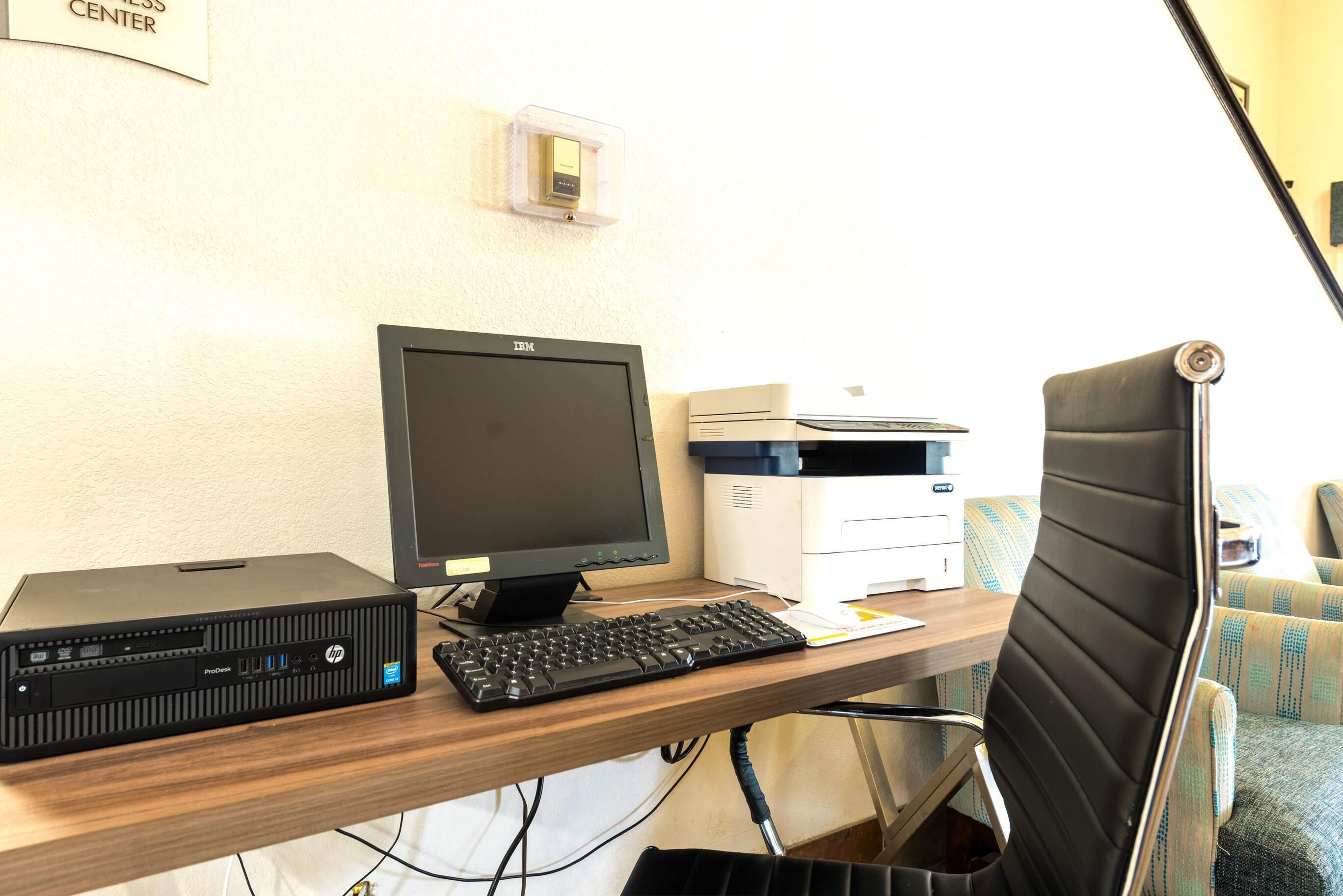 Un escritorio con una computadora HP ProDesk, un monitor, un teclado e impresora.