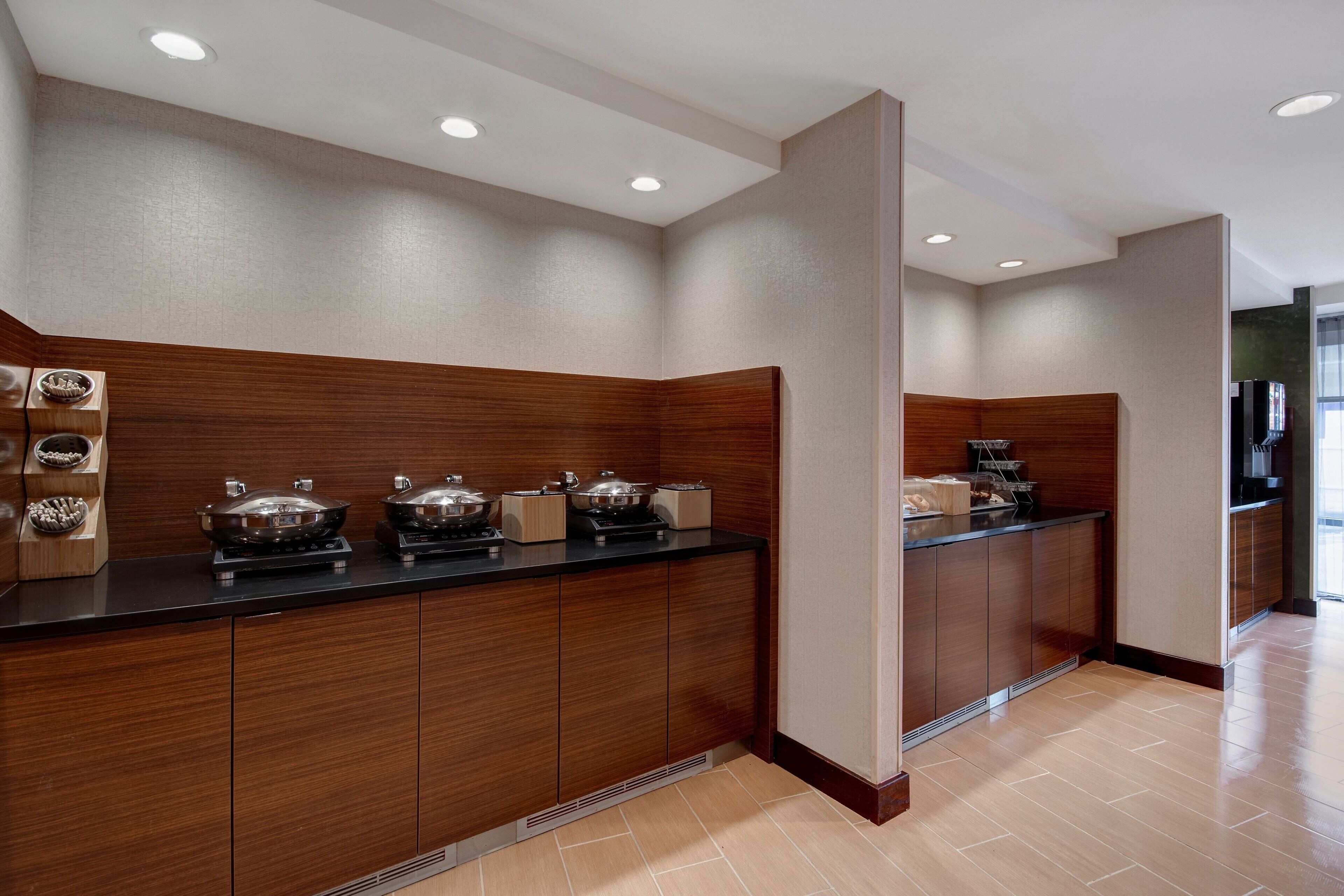 Una cocina moderna con armarios de madera, encimera negra y suelo de baldosas.