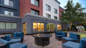 Une terrasse extérieure aménagée avec des meubles en osier et un foyer.