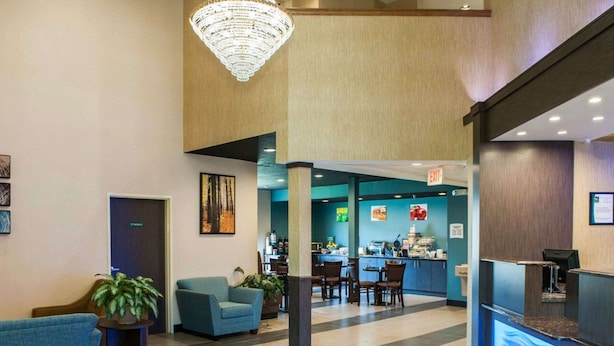 A hotel lobby with a reception desk, seating area, and a view into the dining area.