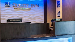 A reception desk at Quality Inn by Choice Hotels with a blue wave design on the wall.