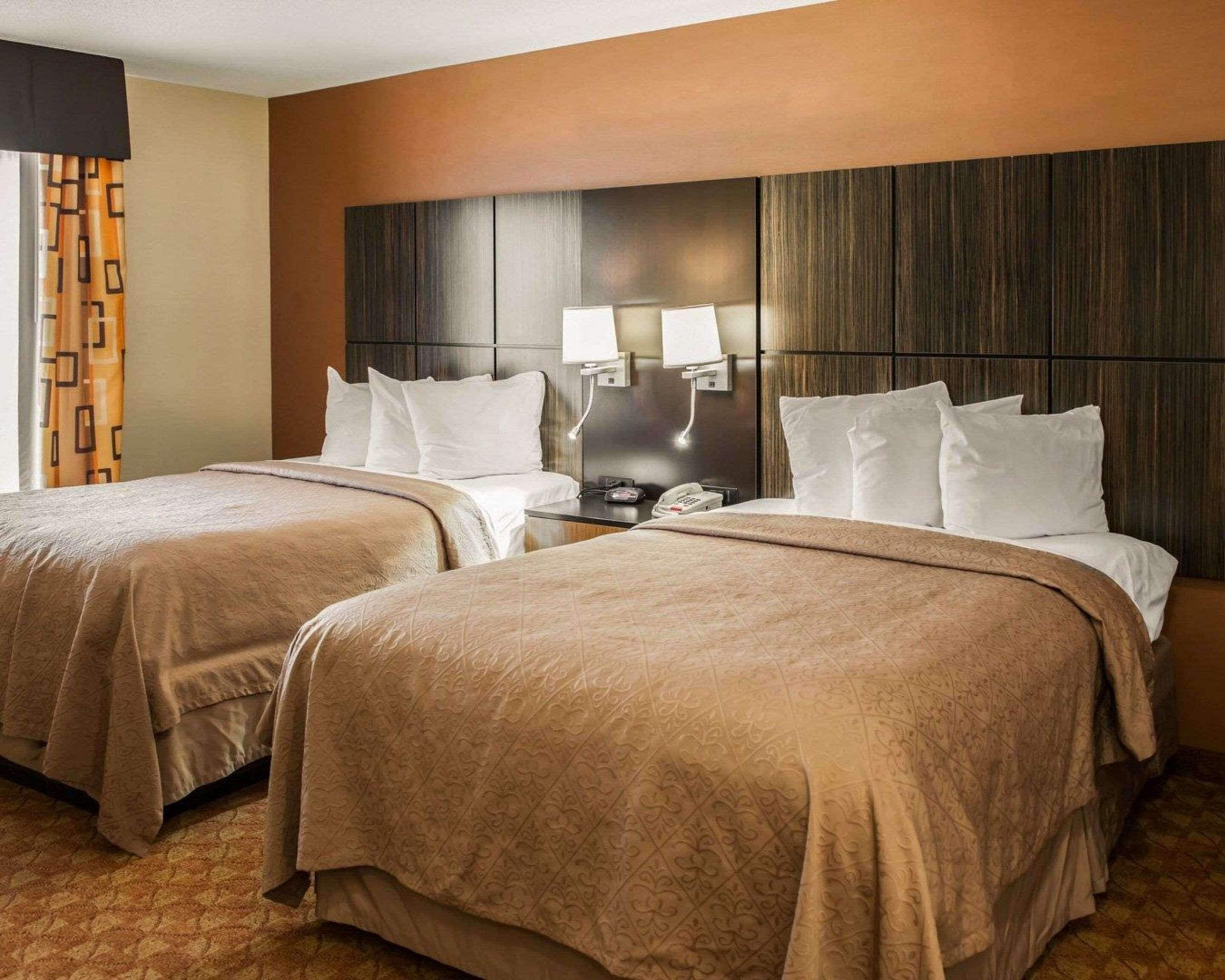 Habitación de hotel con dos camas, una mesita de noche, una lámpara y un teléfono.