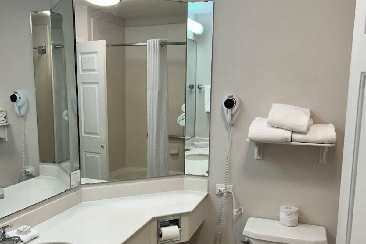Ein Badezimmer mit weißem Waschbecken, Toilette, Dusche und Spiegel.
