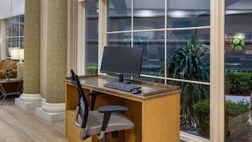A workspace with a computer, chair, and window with a view of greenery.