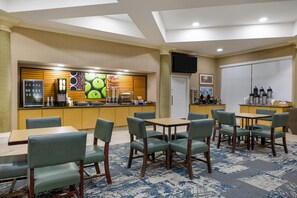 A hotel lobby with a self-service breakfast bar, seating area with tables and chairs, and a flat-screen TV mounted on the wall. - La Quinta Inn & Suites by Wyndham Albuquerque West (Albuquerque)