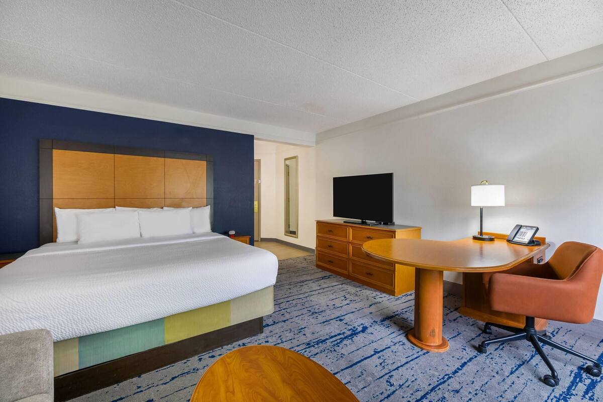 Ein Hotelzimmer mit Bett, Schreibtisch mit Stuhl, Fernseher und Lampe.