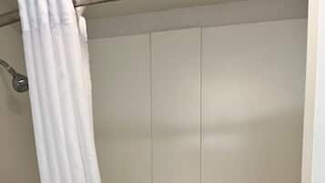 A bathroom with a white shower curtain, a grab bar, and a white bathtub.