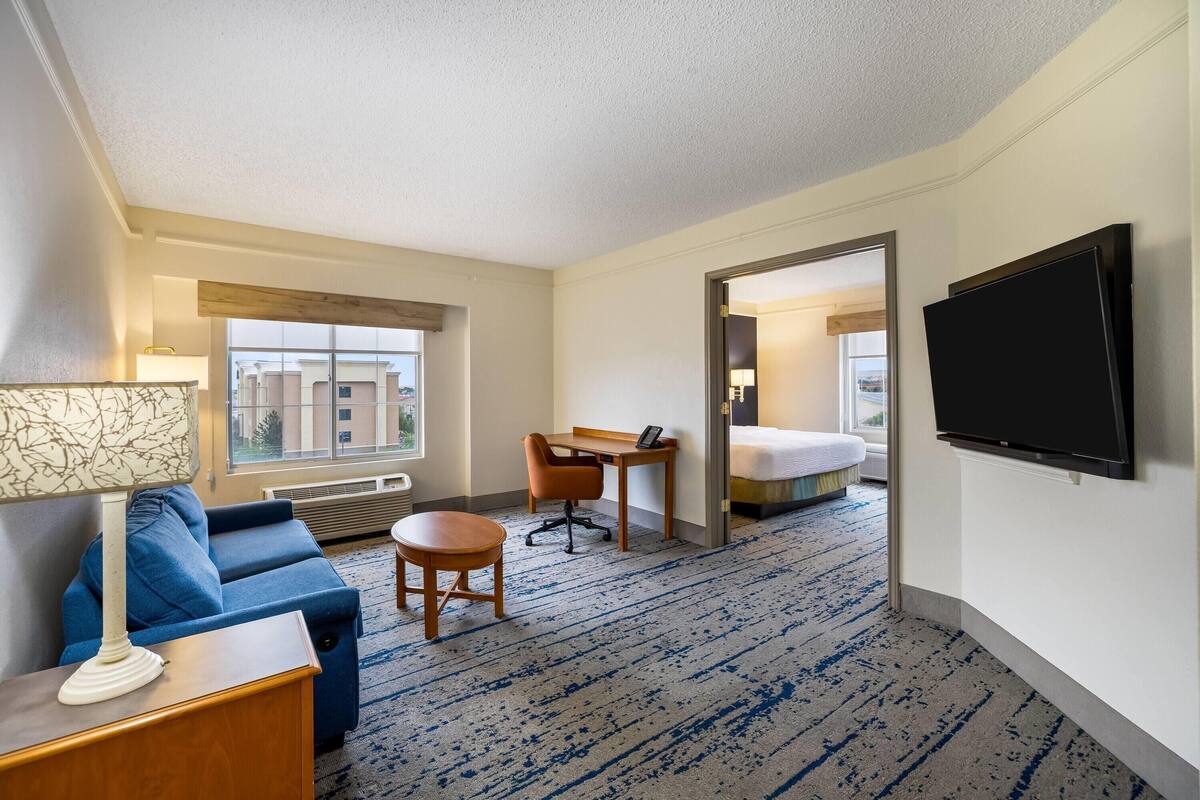 Ein Hotelzimmer mit Sofa, Schreibtisch, Stuhl, Fernseher und einem Bett.