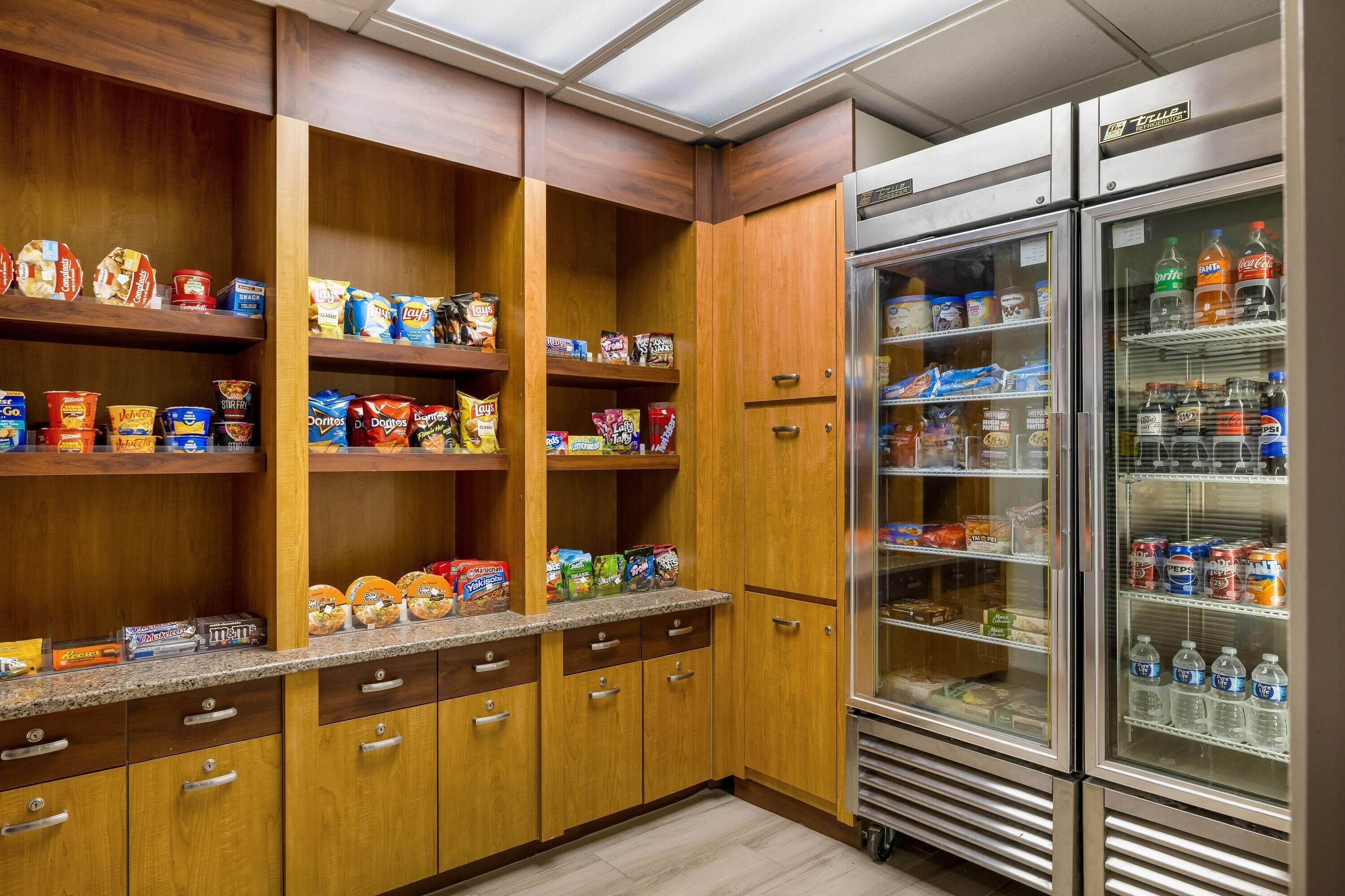A kitchen with wooden cabinets, a granite countertop, and a stainless steel refrigerator.