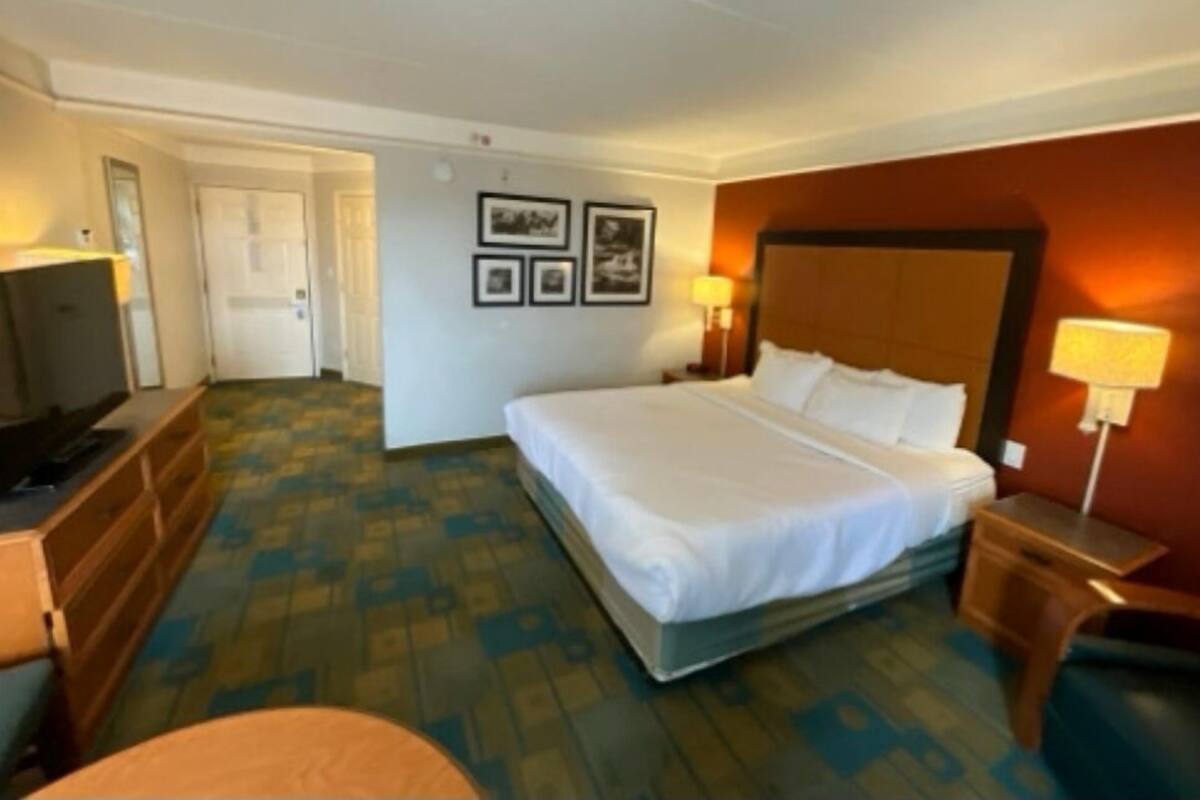 Ein Hotelzimmer mit einem Bett, einem Fernseher, einem Schreibtisch und einem Sessel.