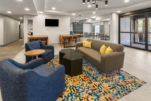 A modern lounge area with seating, a coffee table, and a patterned rug.