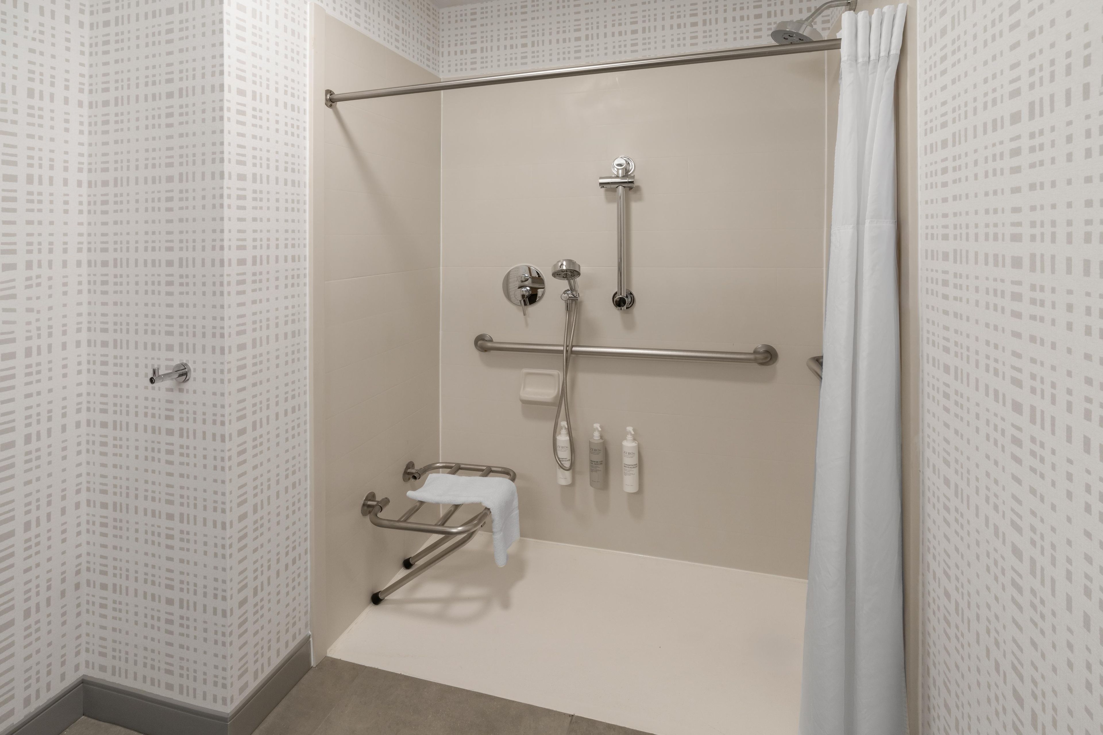 A walk-in shower with a grab bar, a towel rack, and a showerhead.