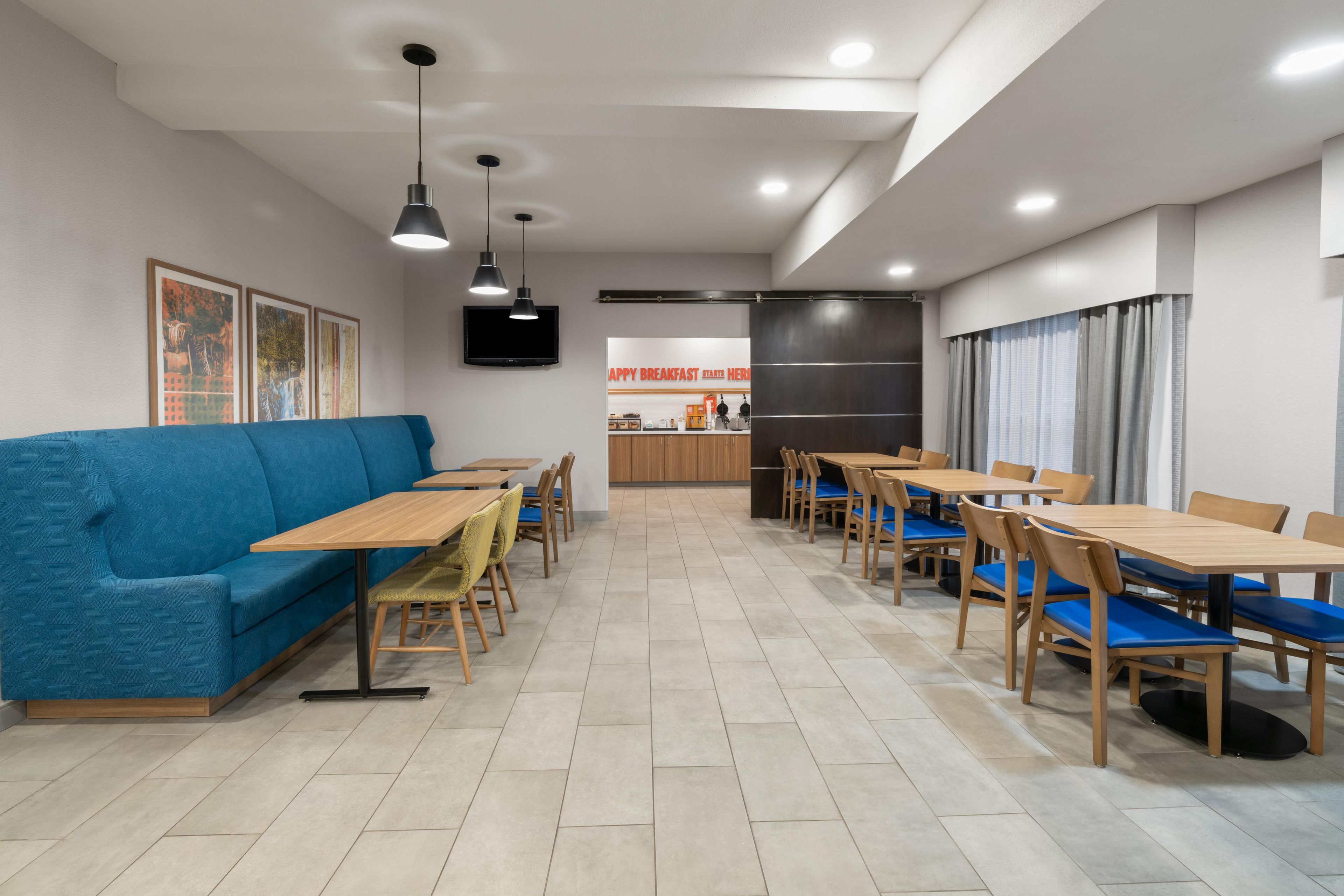 Un espace repas moderne avec un canapé bleu, des tables et des chaises en bois.