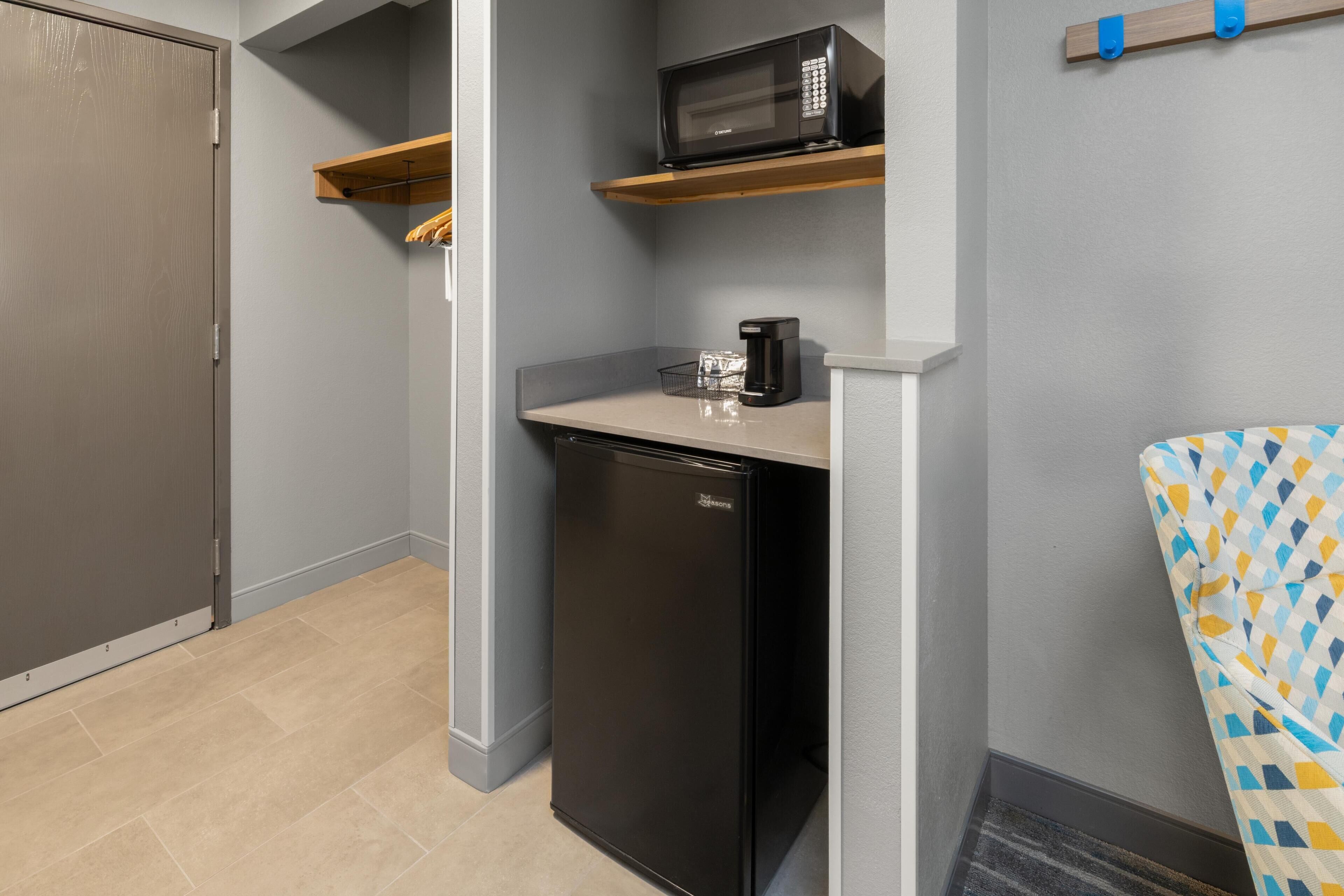 A compact kitchenette with a microwave, coffee maker, and a dishwasher.