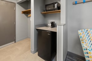A compact kitchenette with a microwave, coffee maker, and a dishwasher.