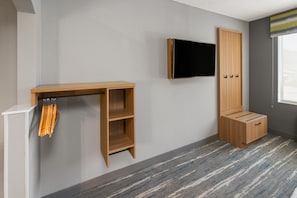 A room with a flat-screen TV mounted on the wall, a wooden cabinet with drawers, and a small desk with a chair. - Hampton Inn Glenwood Springs (Glenwood Springs)