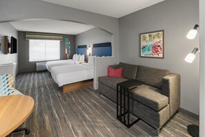 Habitación de hotel con cama, sofá, escritorio y televisor.