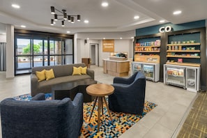 Un vestíbulo moderno con asientos, mostrador de recepción y bar de aperitivos.