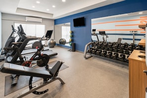 A gym with exercise equipment including treadmills, stationary bikes, and a weight rack.