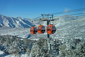 A cable car system with three orange gondolas against a snowy mountain backdrop. - Hampton Inn Glenwood Springs (Glenwood Springs)