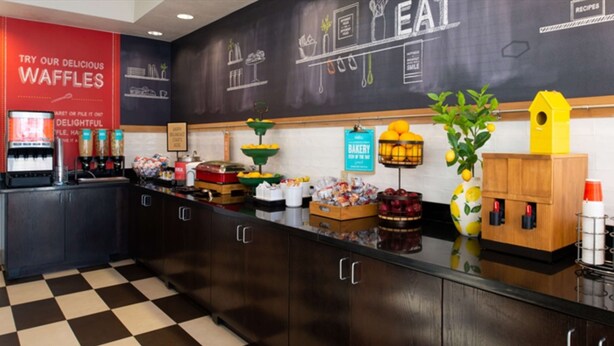 A bakery counter with waffle display, coffee machines, and a chalkboard menu. - Hampton Inn Glenwood Springs (Glenwood Springs)