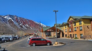 Un hotel con vistas a la montaña, un estacionamiento y cielo despejado.
