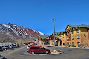A hotel with a mountain backdrop, a parking lot, and a clear sky. - Hampton Inn Glenwood Springs (Glenwood Springs)