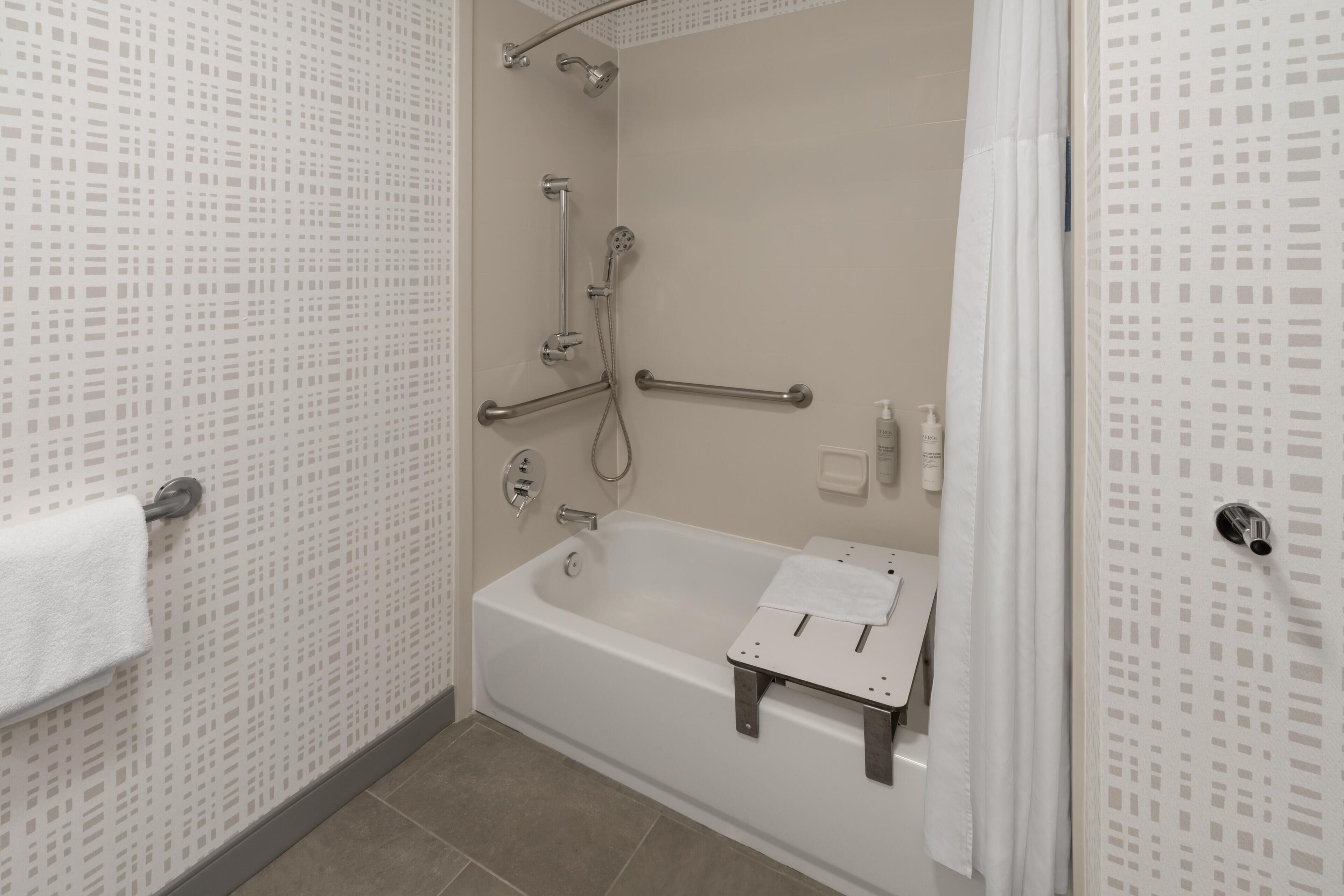 Un baño con bañera, ducha, barandilla y toallero.