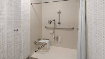 A walk-in shower with a grab bar, a towel rack, and a showerhead.