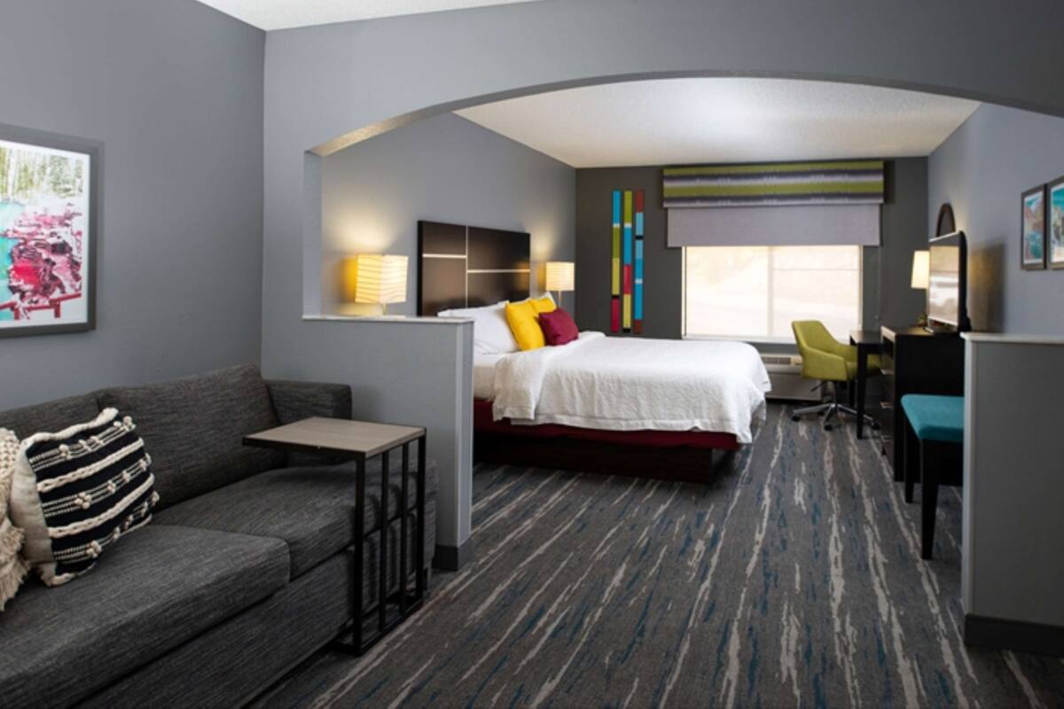 Una habitación de hotel moderna con cama, sofá, escritorio y silla.
