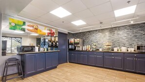 A modern kitchen with dark cabinets, a tiled backsplash, and a variety of appliances. - Quality Inn & Suites CVG Airport (Hebron)