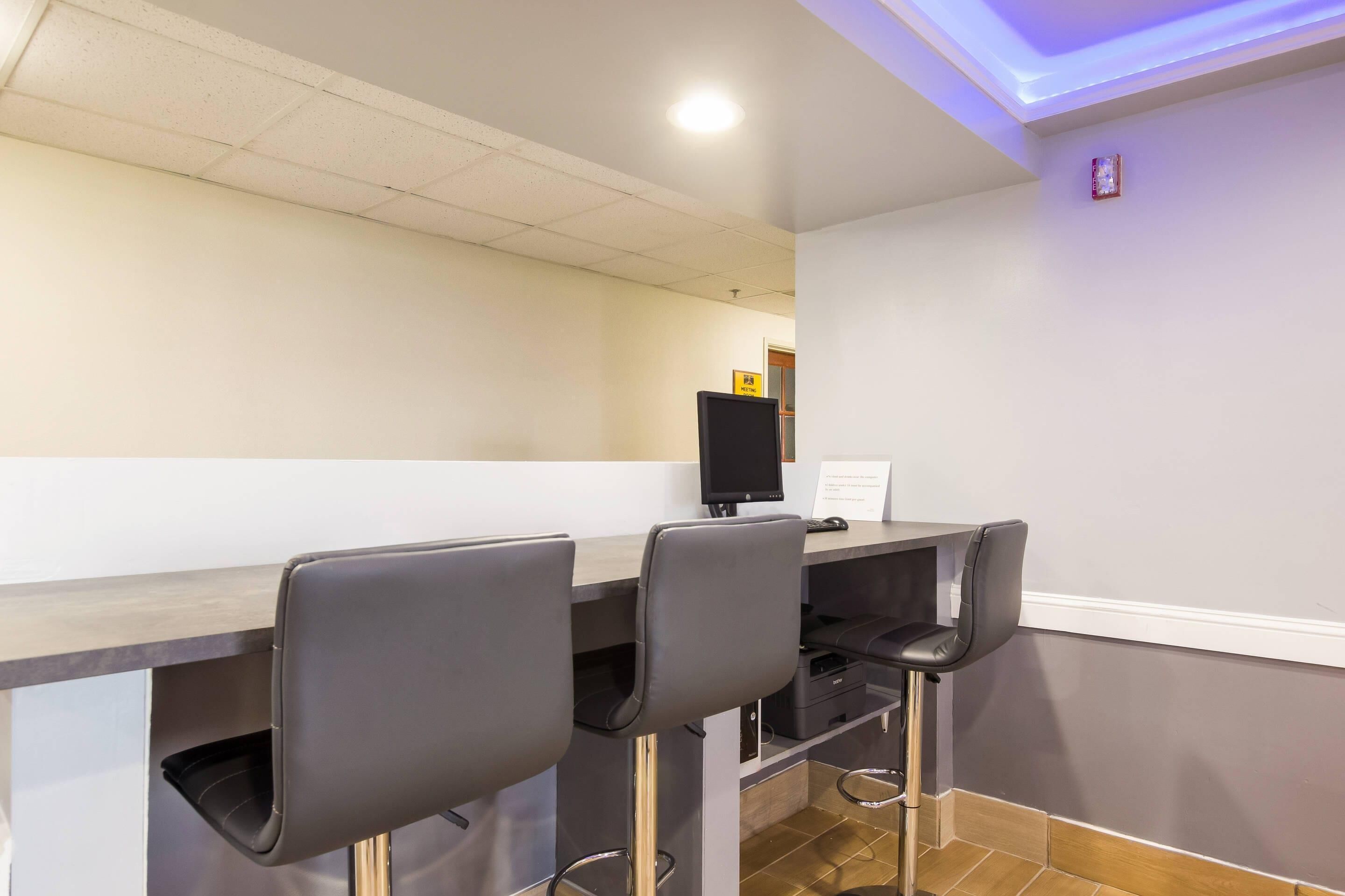 A bar area with a counter, two bar stools, a television, and a small sign on the wall.
