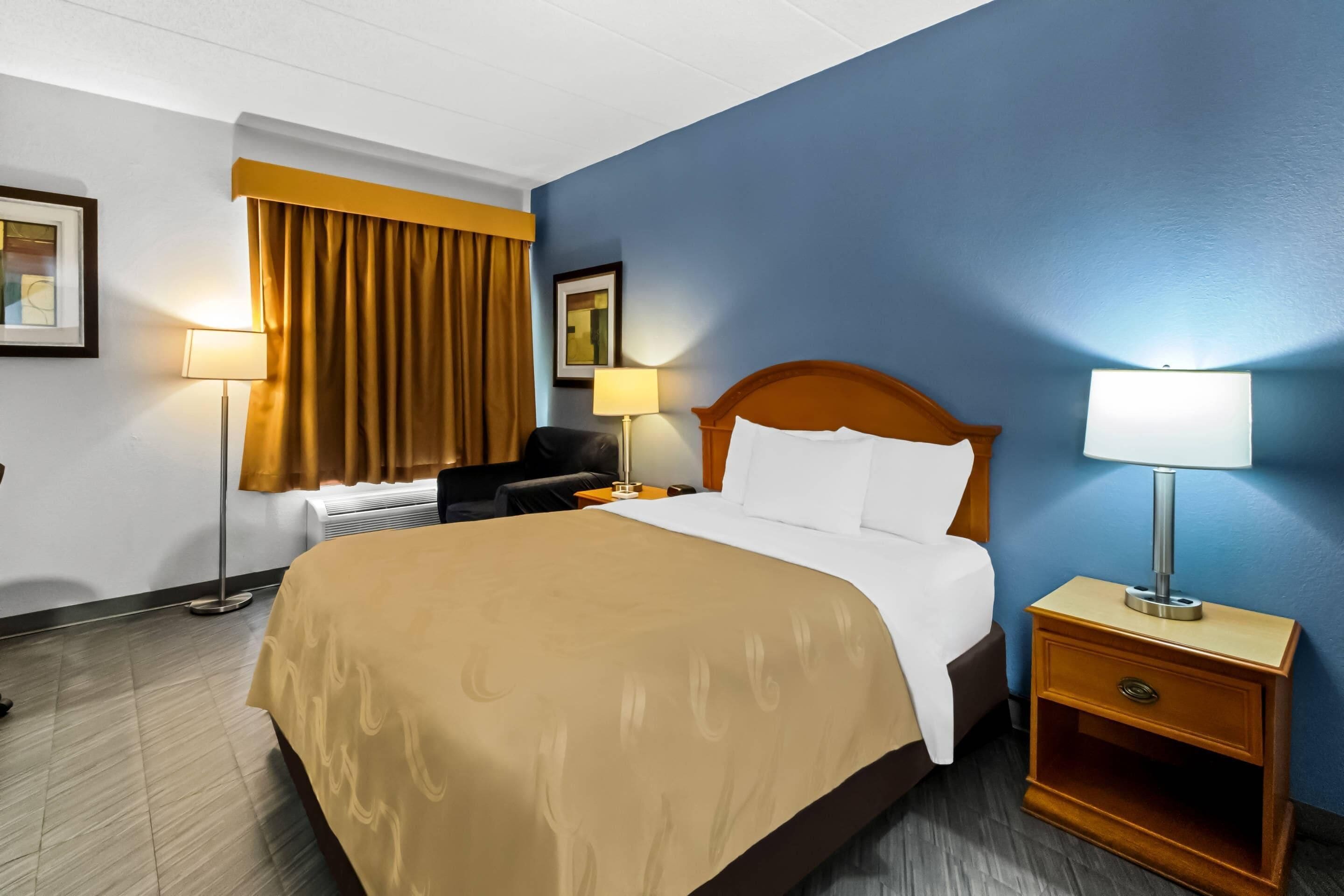 Een hotelkamer met een bed, nachtkastjes, een bureau en een stoel.