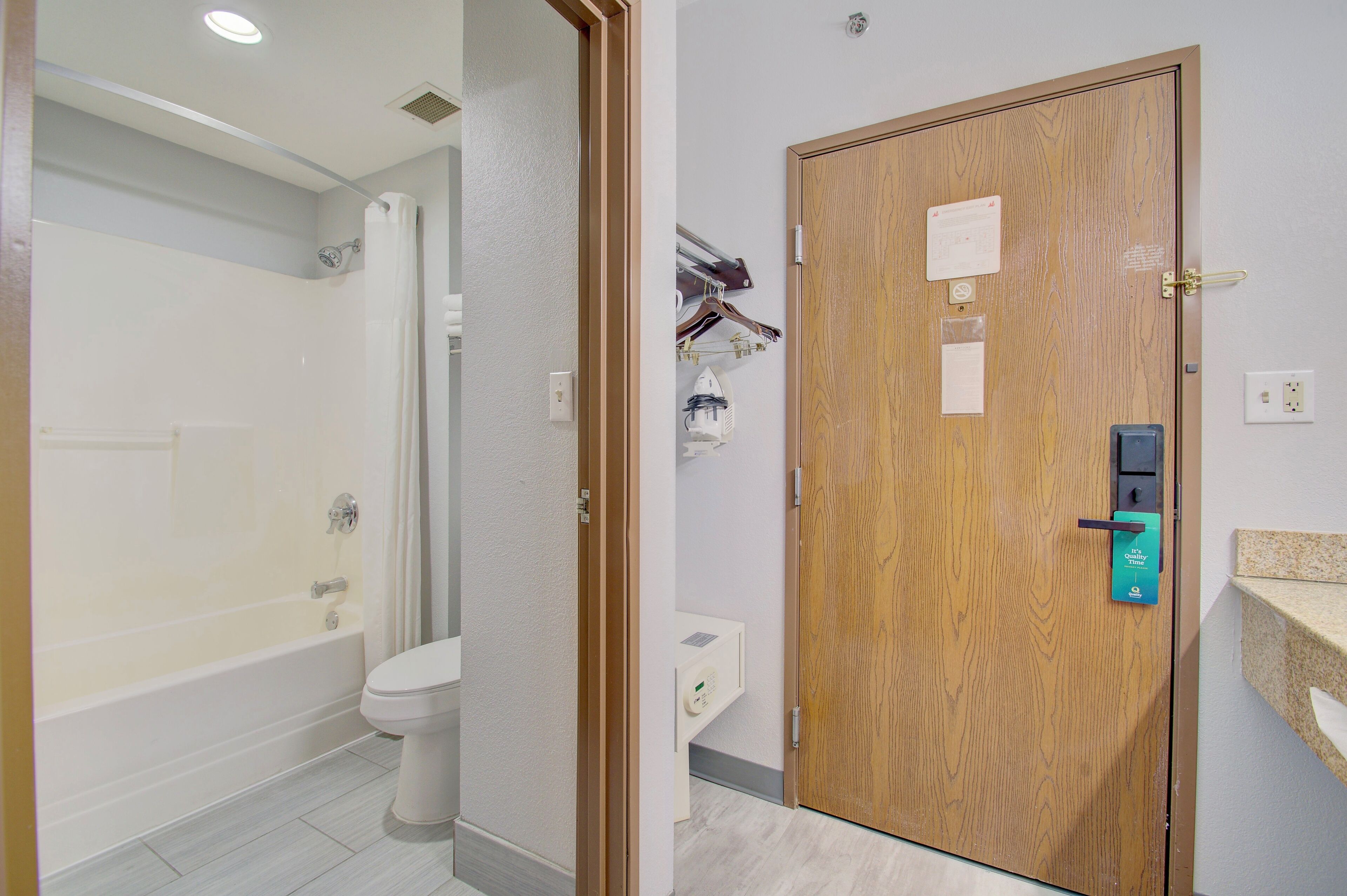Ein Badezimmer mit Badewanne, Toilette und einer Holztür mit Schloss und einem kleinen Schild.