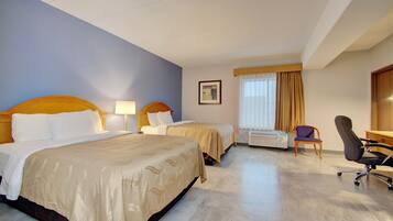 A hotel room with two beds, a desk, a chair, and a window with curtains.