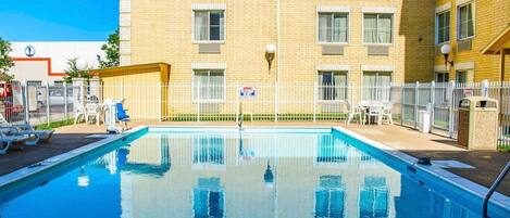 A swimming pool with a clear view of a multi-story building in the background.