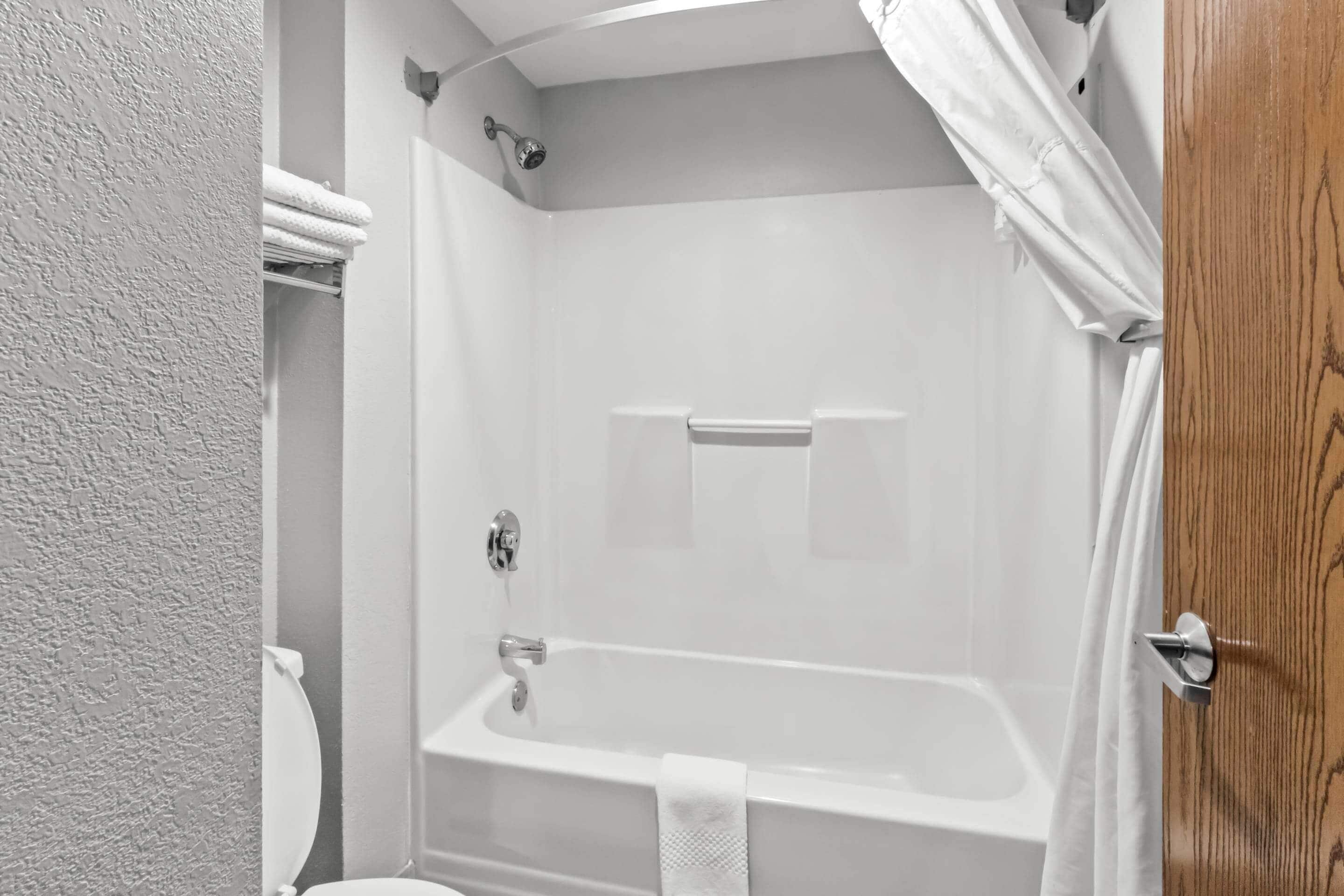 A bathroom with a bathtub, a shower curtain, and a towel rack.