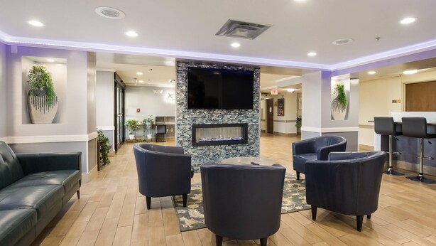 A lobby with a fireplace, seating area, and a bar. - Quality Inn & Suites CVG Airport (Hebron)