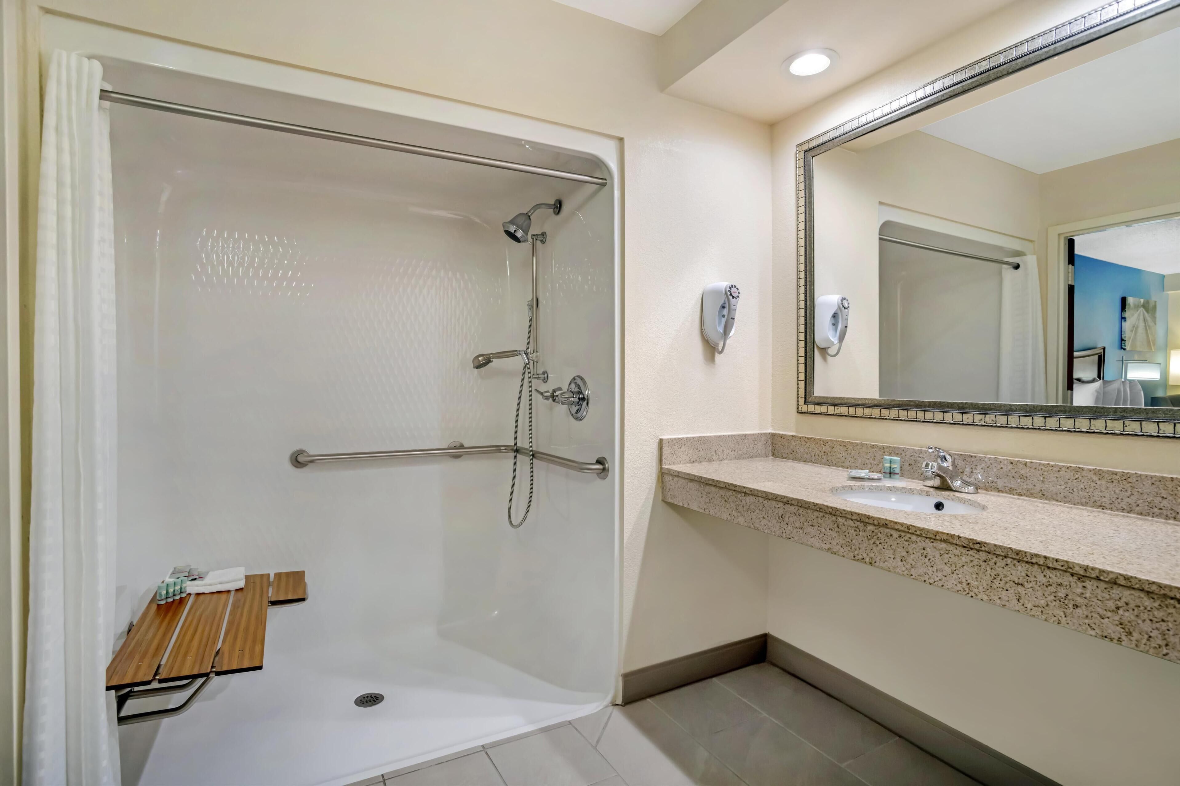 A modern bathroom with a glass-enclosed shower, a vanity with a sink, and a large mirror.